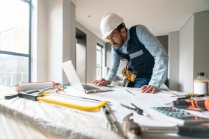 Building contractor working in a house renovation and using his laptop